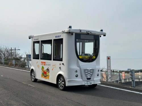 Auve Tech autonomous shuttle driving on a rural road, featuring local branding, providing an innovative rural mobility solution